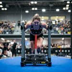 Peserta HYROX sedang mendorong sled push di kompetisi indoor fitness