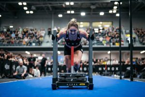 Peserta HYROX sedang mendorong sled push di kompetisi indoor fitness