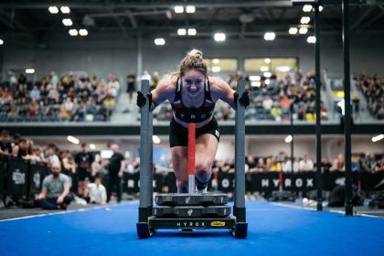 Peserta HYROX sedang mendorong sled push di kompetisi indoor fitness