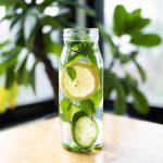 infused water lemon timun mint dalam botol kaca dengan latar belakang kayu dan daun segar
